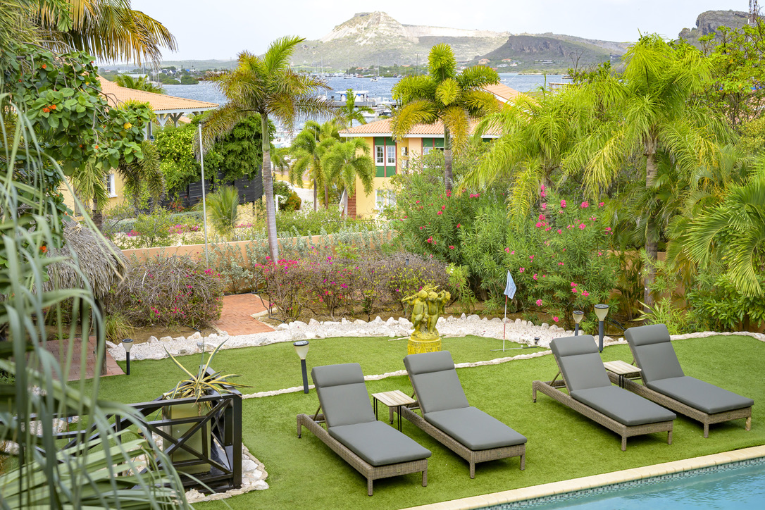 Bay and mountain view beyond the pool loungers at Bayside Hill