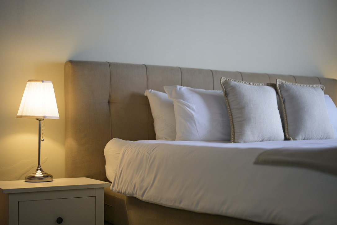 Upholstered bed beside the reading lamp at Bayside Hill