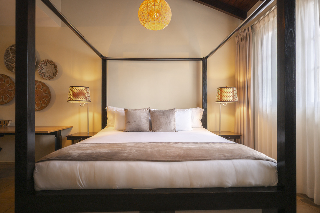 Four-poster bed beneath the wooden ceiling at Bayside Hill