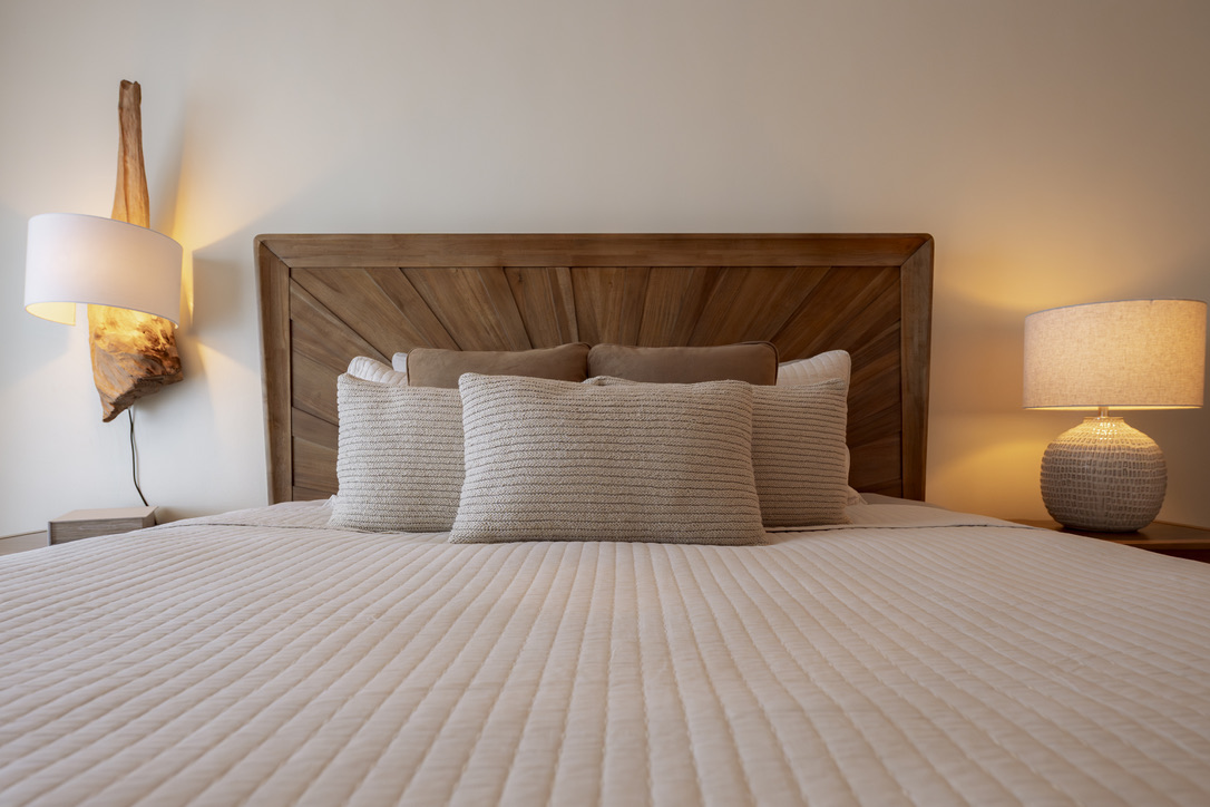 Carved headboard and layered pillows in the first bedroom