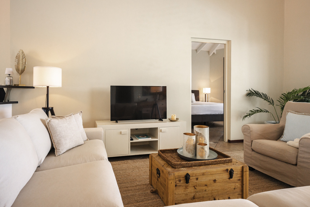 Living room with sofa, armchair and television at Palm Breeze