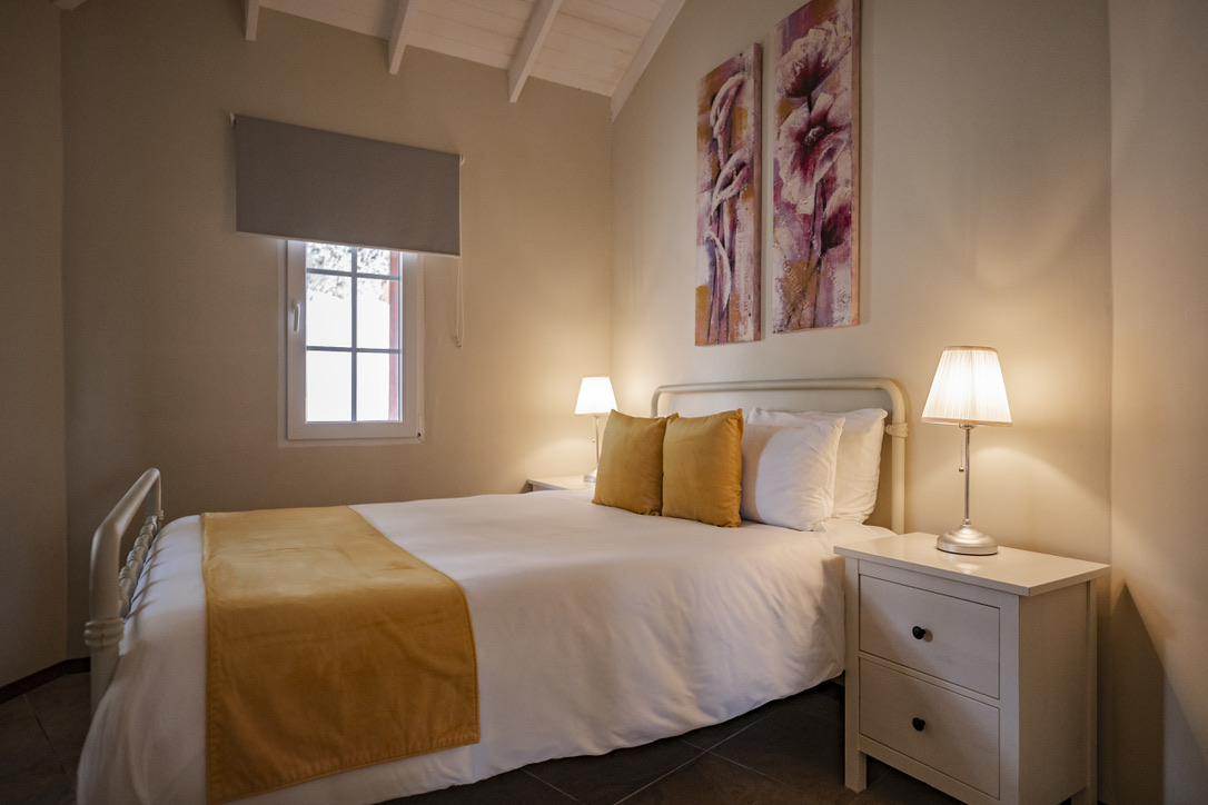 Bedroom with yellow cushions and floral artwork at Palm Breeze