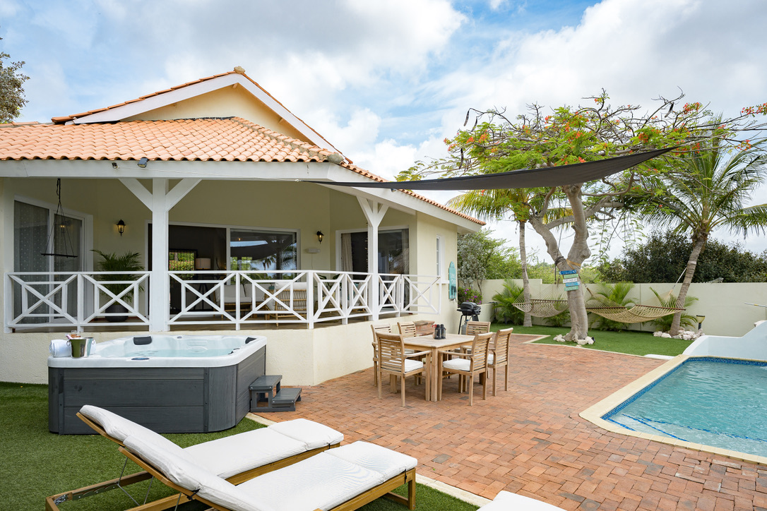 House, hot tub and outdoor dining beside the pool at Palm Breeze