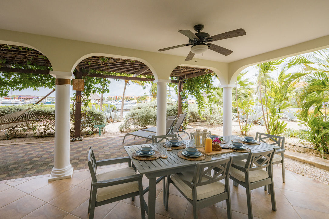 Covered porch dining with garden and marina views